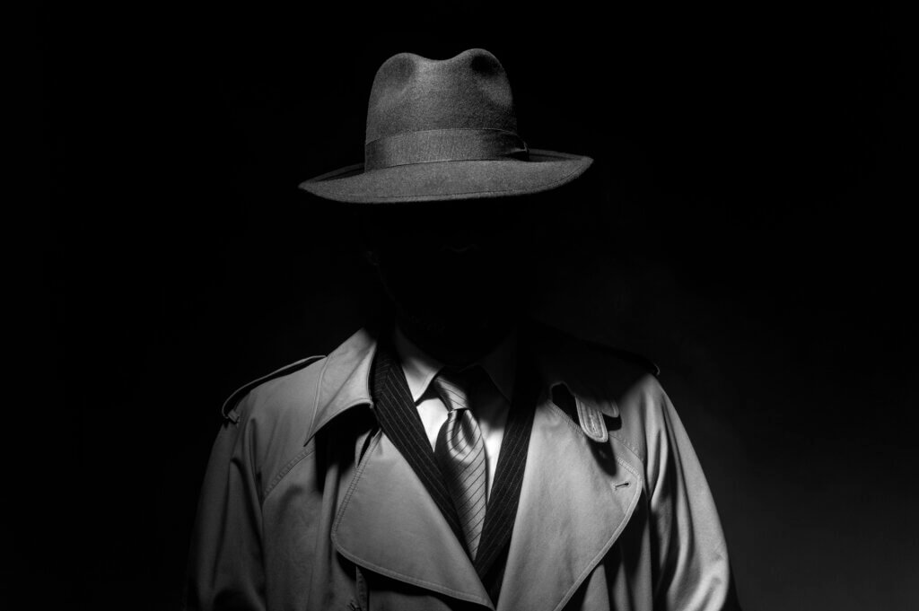 Your WordPress Site Is Being Attacked Right Now. AI Just Made It Worse. 1 Man posing in the dark with a fedora hat and a trench coat, 1950s noir film style character